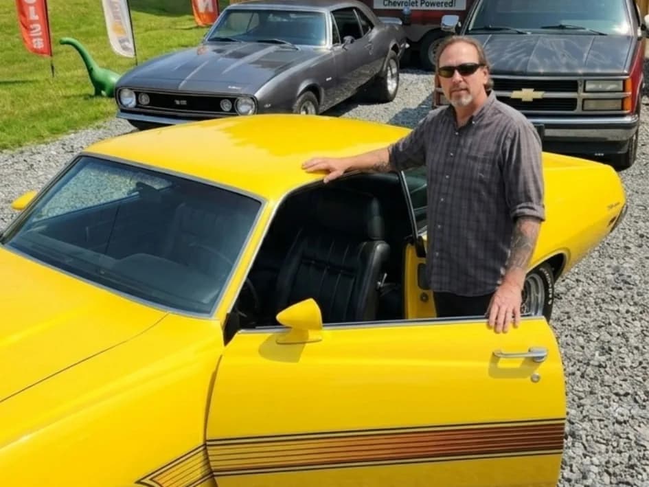 A man standing with his bright yellow 1970 Ford Torino GT at a Yabba Dabba Dogs classic car meetup